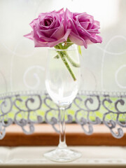Ping roses small bouquet in a wine glass by a window, Light and airy look.