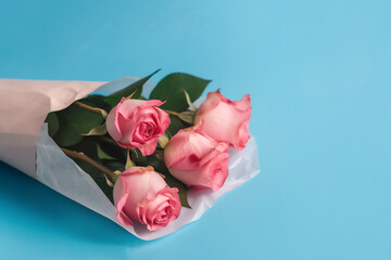 Fototapeta premium Beautiful pink and coral colored roses in wrapping tissue on blue background. Flowers for lovers. Festival floral photo with copy space. Mother day, International Women Day, Birthday, Fathers Day