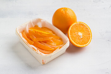 Wicker birch basket with fresh juicy candied oranges with fresh juicy orange on a light gray background