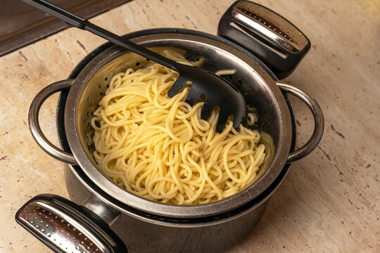 boiled ready-made spaghetti in a colander and a kitchen saucepan