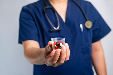 doctor holds in his hands different pills in a glass and offers them to the patient in the clinic. Close-up
