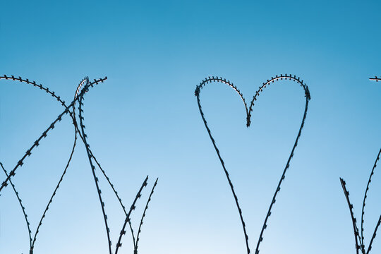 Heart shaped barbed wire. Barbed wire in the shape of a heart, photographed against a blue sky.
