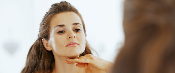 Young woman examining facial skin condition