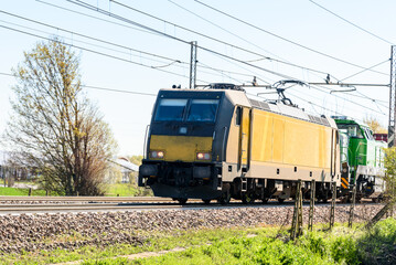 Powerful electric locomotive pulling a cargo train on a suny spring day