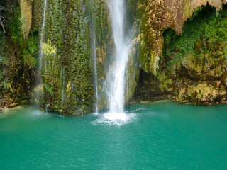 Close-up photo of the end of the Sillans-la-Cascade waterfall in the Var department in Provence in France falling into an expanse of turquoise blue colored water reminiscent of a lagoon