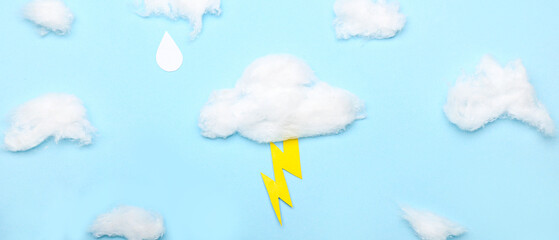 Clouds made of cotton wool and paper lightning on light blue background