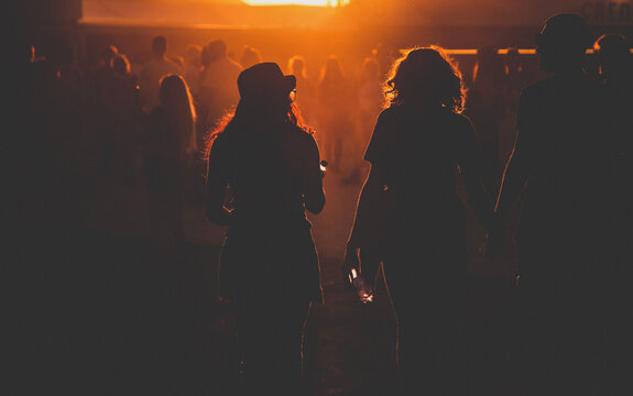 silhouettes of people walking at sunset festival