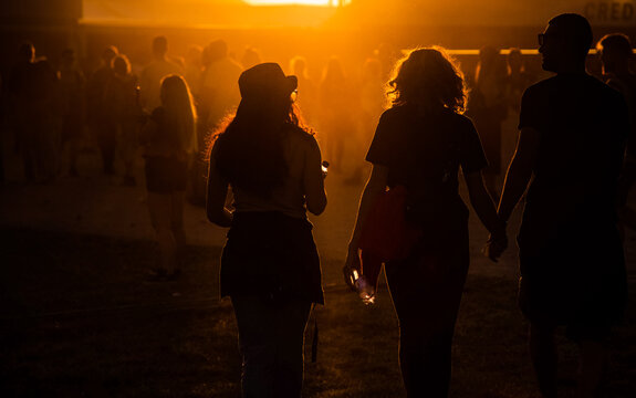 silhouettes of people walking at sunset festival