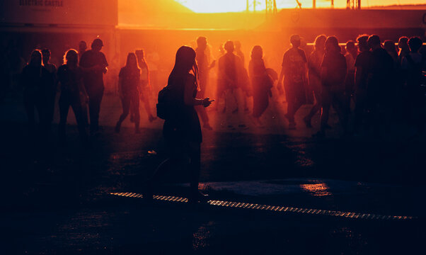 silhouettes of people walking at sunset festival - Powered by Adobe