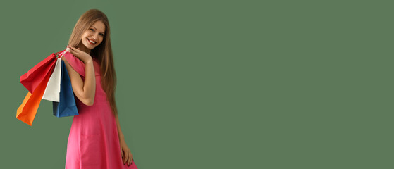 Beautiful young woman with shopping bags on green background with space for text