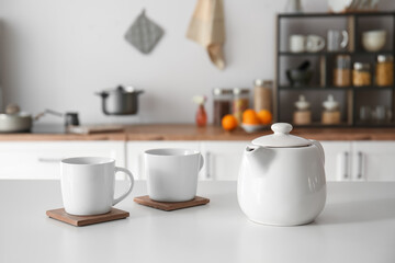 Fototapeta na wymiar Teapot with cups on table in modern kitchen