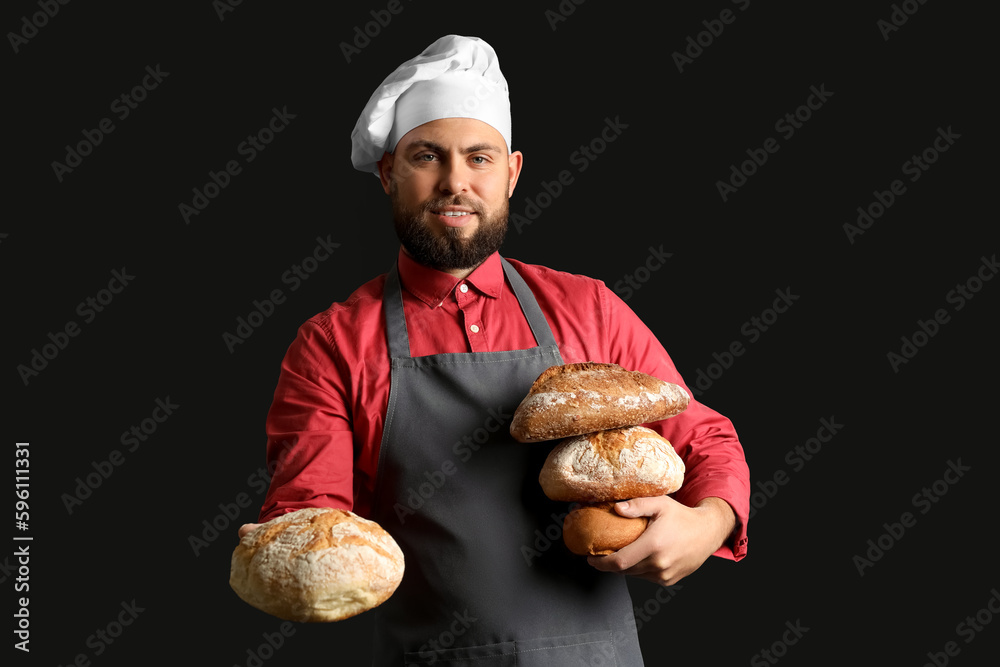 Canvas Prints Male baker with loaves of fresh bread on dark background