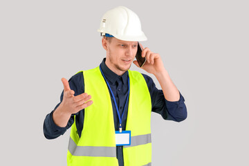 Male worker talking by phone on grey background