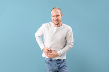 Young man with appendicitis on blue background