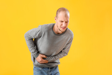 Young man with appendicitis on yellow background