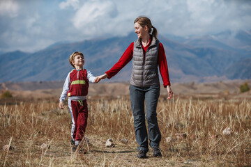 Mother and son walking on mountains background at autumn