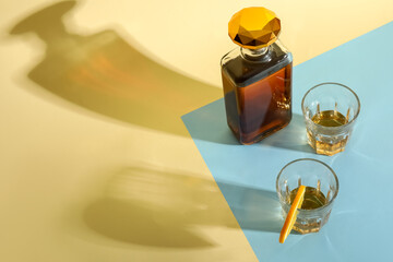 Bottle and glasses of rum with orange slice on colorful background