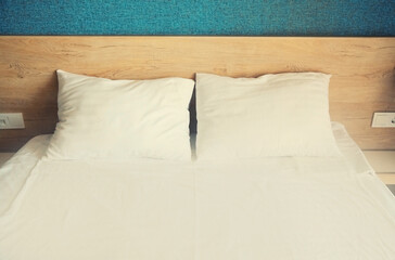 Clean bed with white sheet and pillows in hotel