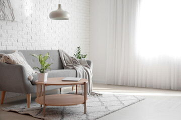 Interior of bright living room with modern laptop on coffee table