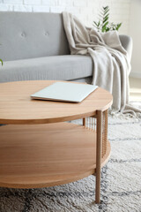 Coffee table with modern laptop in bright living room