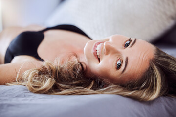 Fototapeta premium Well youre home early. an attractive young woman wearing lingerie and relaxing on the bed at home.