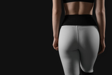 Naklejka premium Sporty young woman in leggings on black background, back view