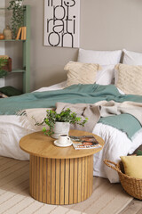 Interior of bedroom with cozy bed and houseplant on coffee table