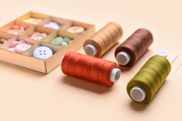 Set of thread spools and buttons on color background, closeup