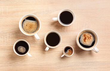 Cups of coffee on light wooden background