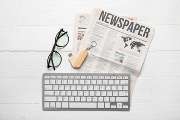 Newspapers with USB flash drive, eyeglasses and computer keyboard on white wooden background