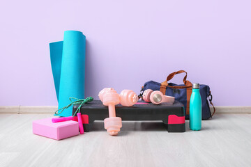 Sports equipment with headphones near lilac wall in gym