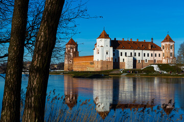 View of architectural ensemble of Mir Castle from pond in sunny winter day, Grodno region, Belarus