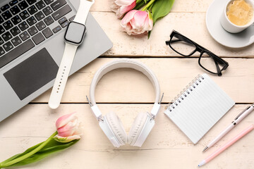 Composition with modern gadgets, eyeglasses and tulip flowers on light wooden background