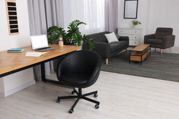 Stylish room interior with comfortable office chair, desk and houseplant