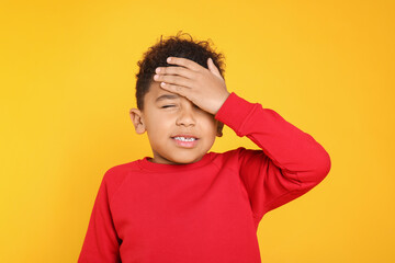 Portrait of emotional African-American boy on yellow background