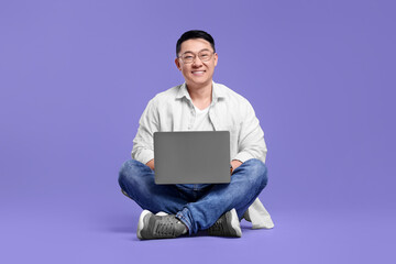 Happy man with laptop on lilac background