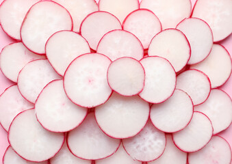 Slices of fresh radish on pink background