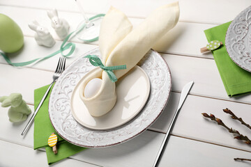 Festive table setting with painted egg, plates and willow twigs. Easter celebration