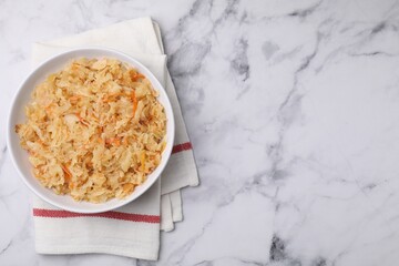 Bowl with tasty sauerkraut on white marble table, top view. Space for text