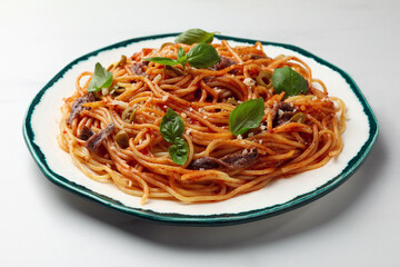 Delicious pasta with anchovies, tomato sauce and basil on white table