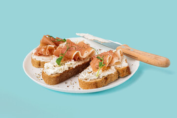 Plate of tasty bruschettas with jamon on blue background