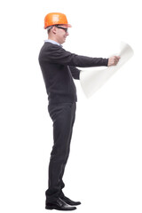 sideview full length portrait of serious businessman in orange hardhat with blueprint looking up