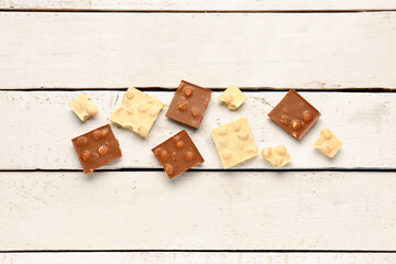 Different tasty chocolate with nuts on  light wooden background