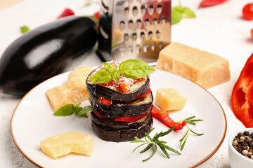 Plate with tasty baked Eggplant Parmesan on light background