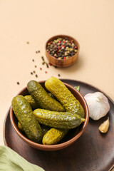 Bowl with tasty fermented cucumbers on beige background
