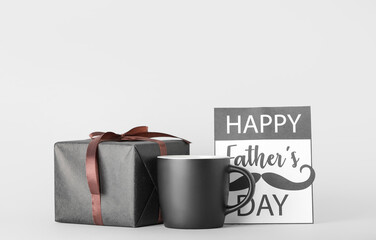 Card for Father's Day with cup of tea and gift on grey background