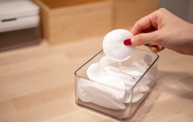 Female hand with new clean cotton pad from the plastic box preparing to clean the face.