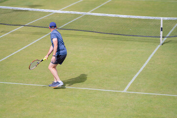Amateur playing tennis at a tournament and match on grass in Europe 