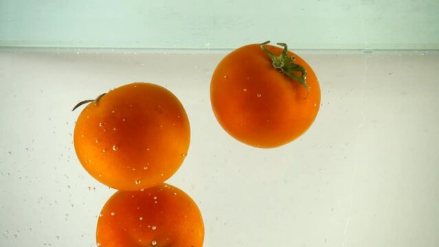 Tomatoes in water. Slow motion.