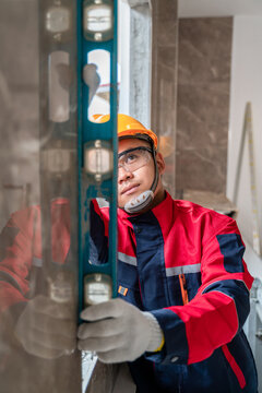 An engineer or inspector wearing a safety gear is inspecting a house by measuring the water level for accuracy. Contractor inspection and construction engineering concept. vertical image.